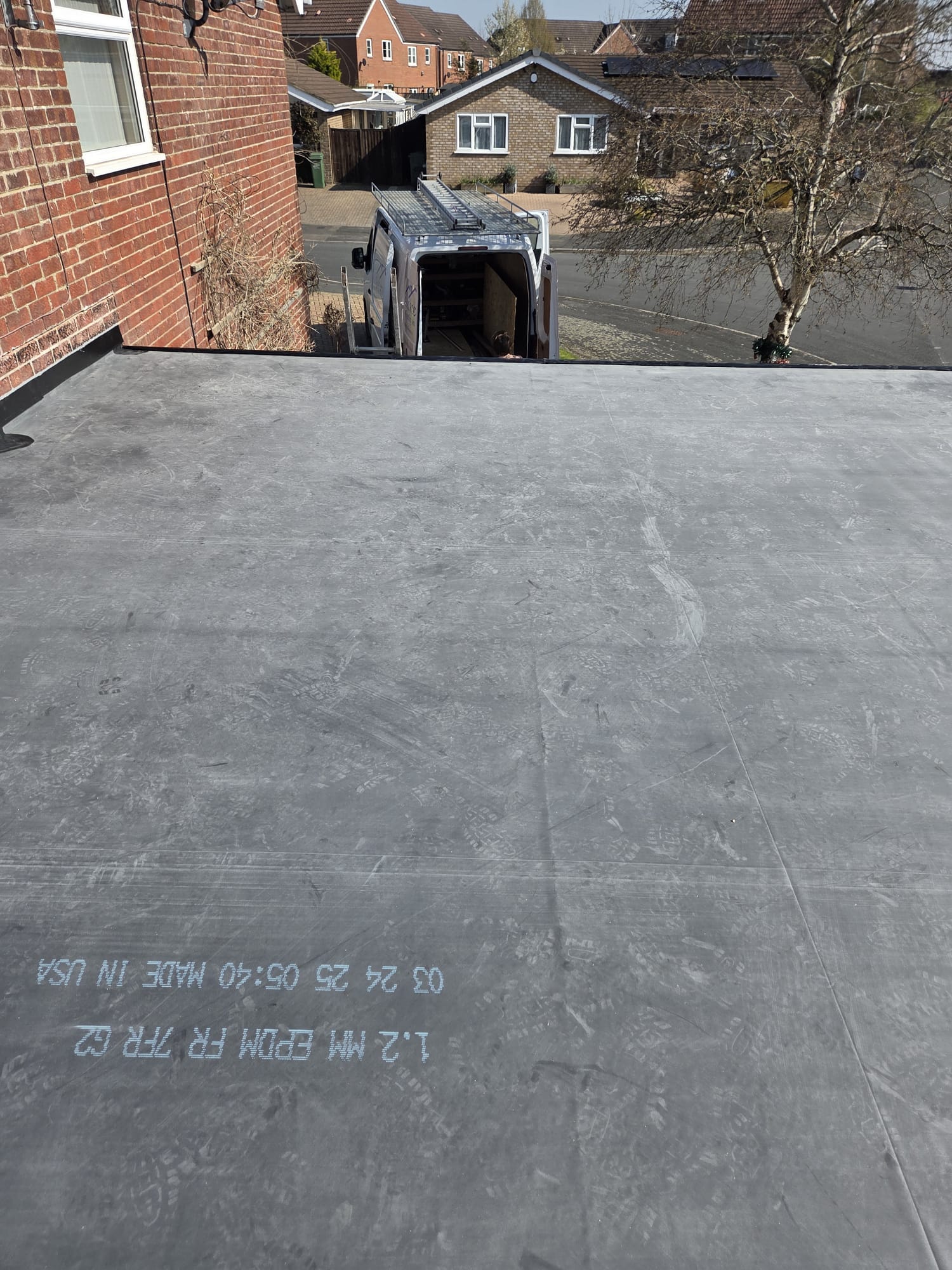Completed EPDM rubber flat roof installation on a rear extension with edge trim in place