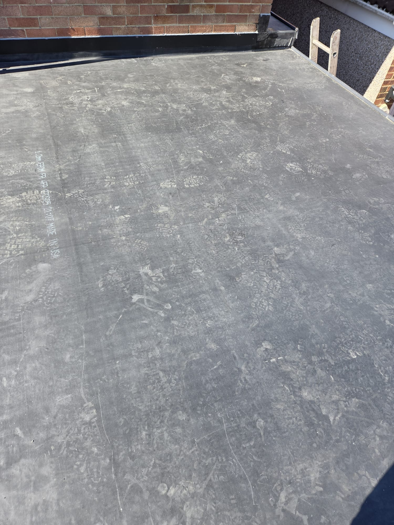 Wide EPDM flat roof installation on a residential extension with neighbouring rooftops behind