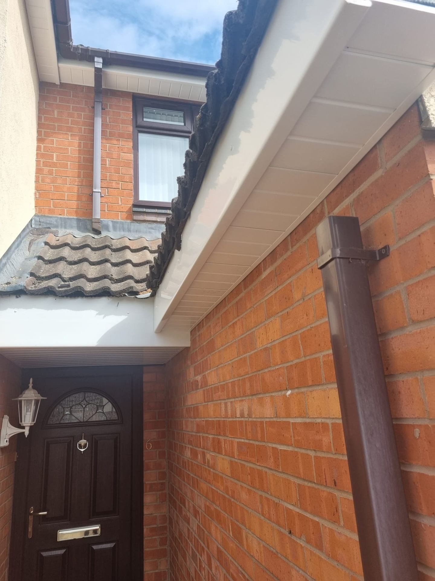 New white fascia and soffit with replacement brown downpipe on a porch entrance