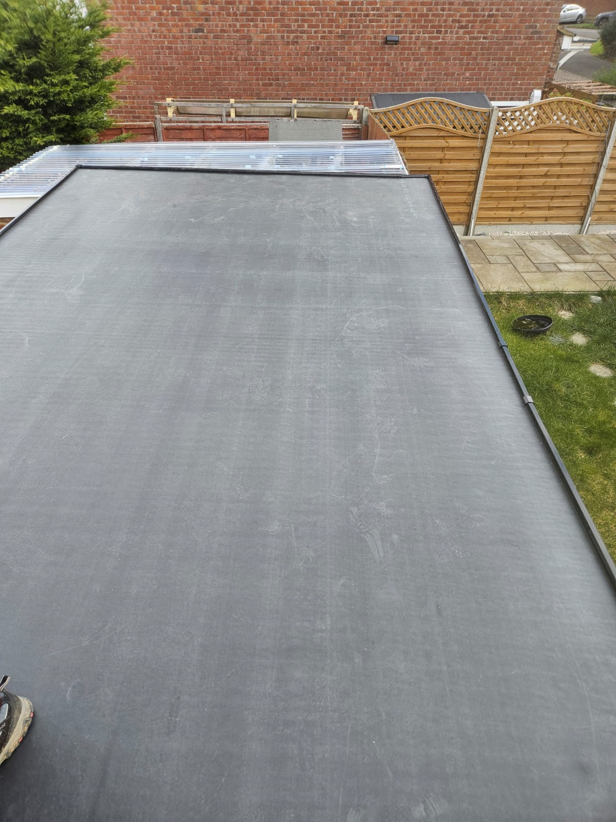 EPDM flat roof membrane finished against a brick parapet wall with black flashing detail