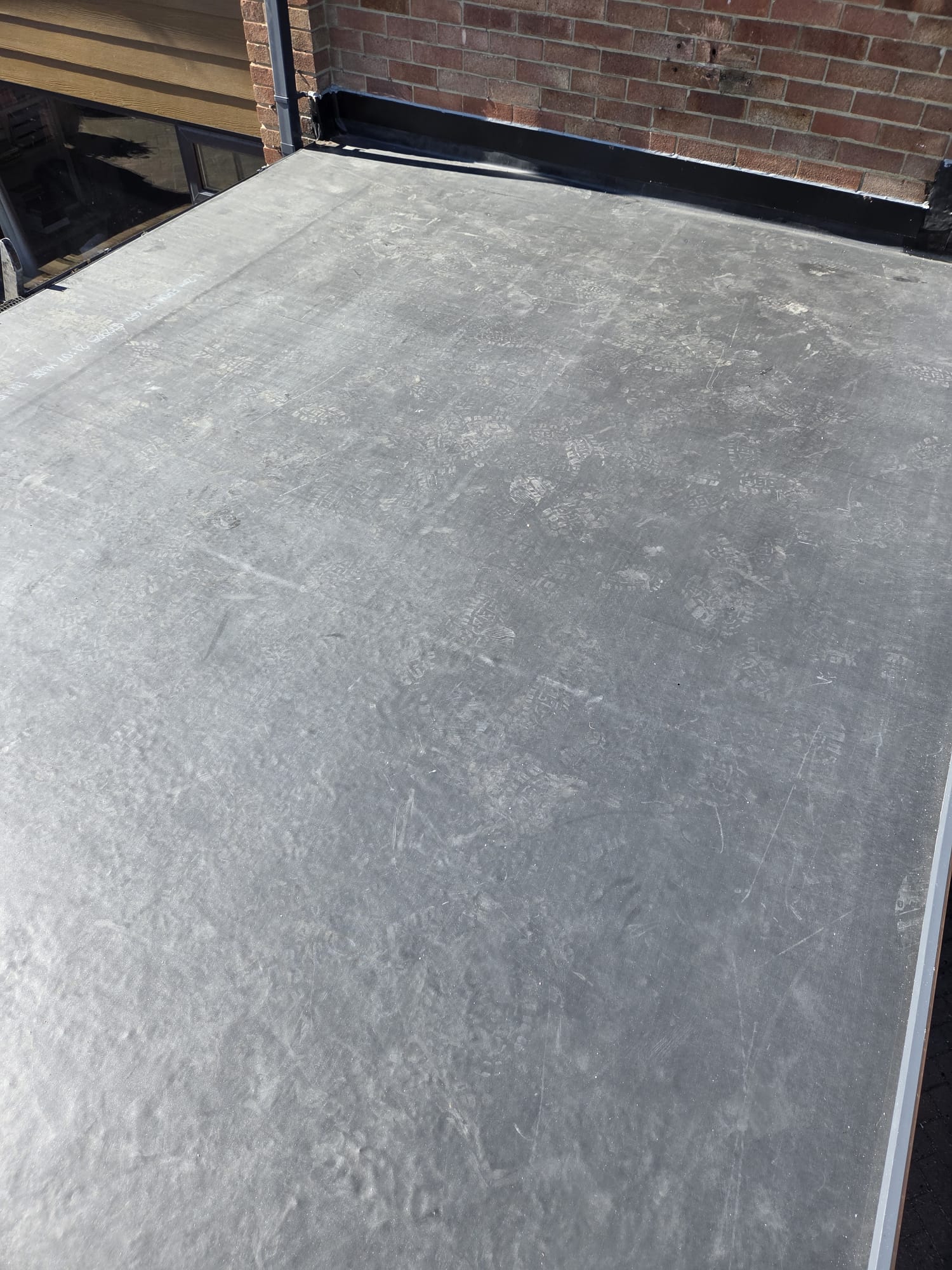 Completed EPDM rubber flat roof on a residential extension beside a conservatory roof