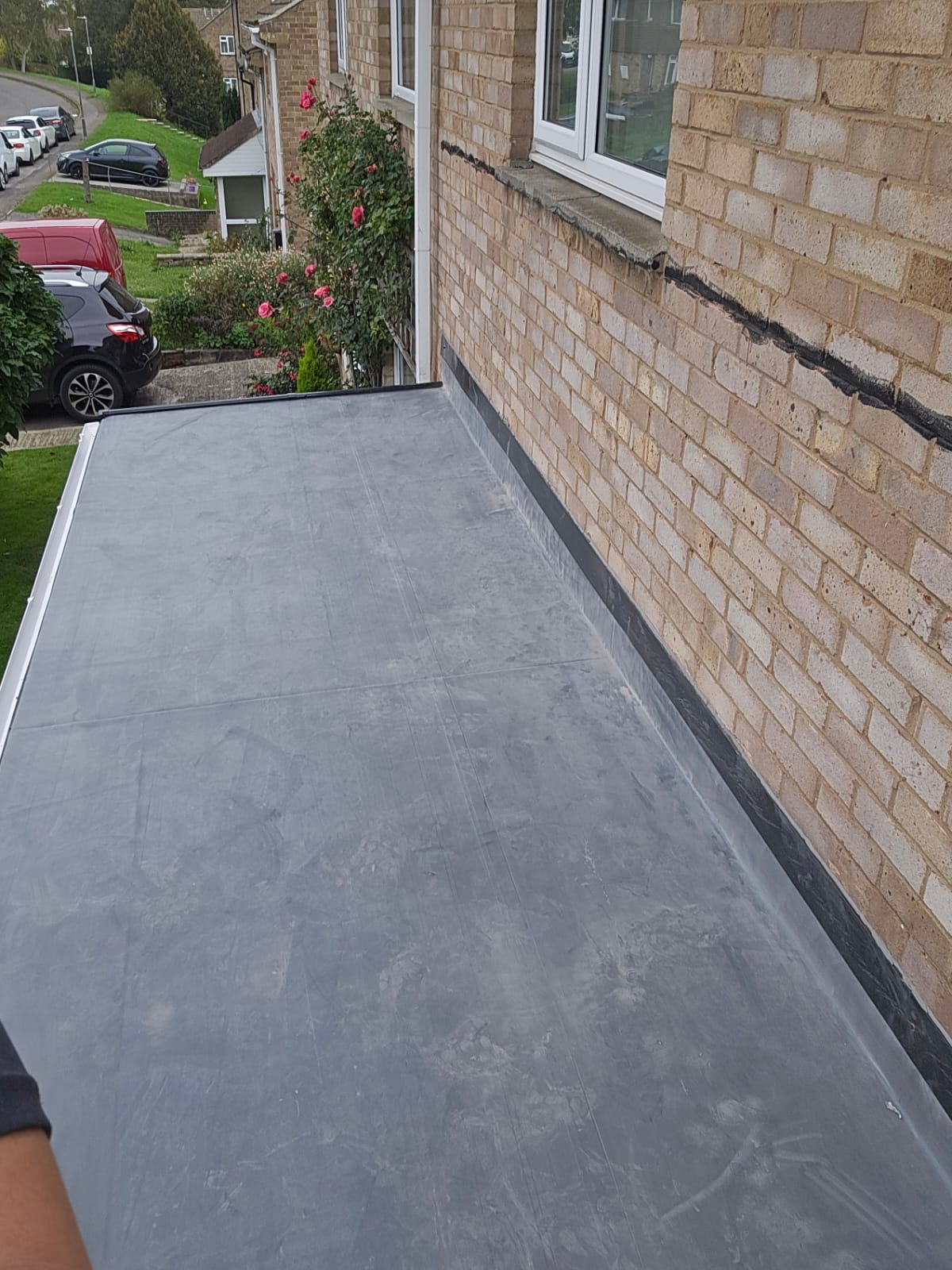 Narrow side-return EPDM flat roof installation beside a cream brick wall