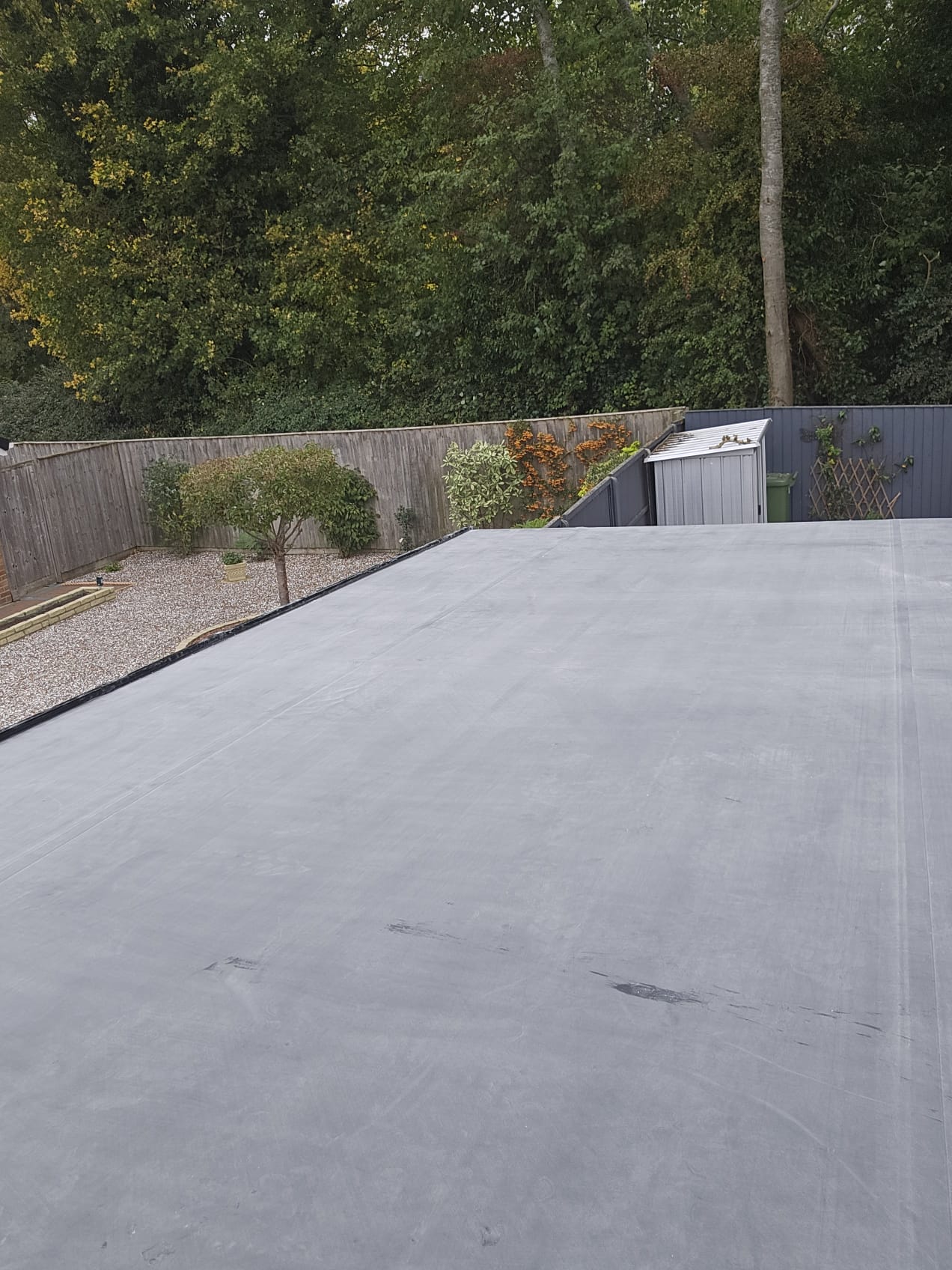 EPDM flat roof installation in progress beside front garden landscaping